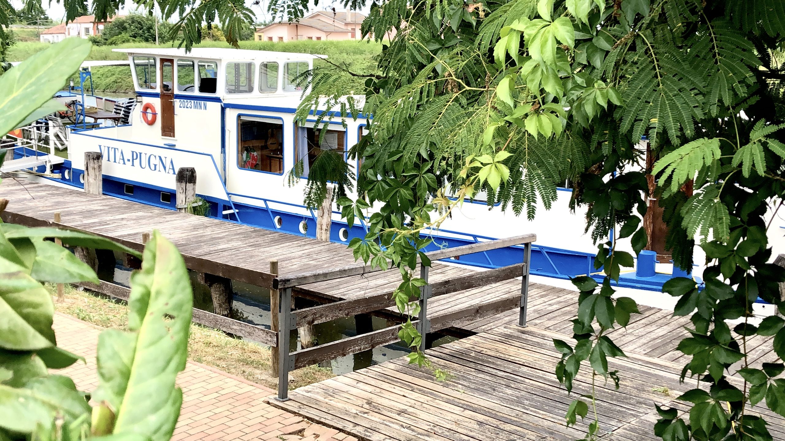 Blau-weißes Girolibero-Boot, das auf einem Ponton entlang des Flusses vertäut ist